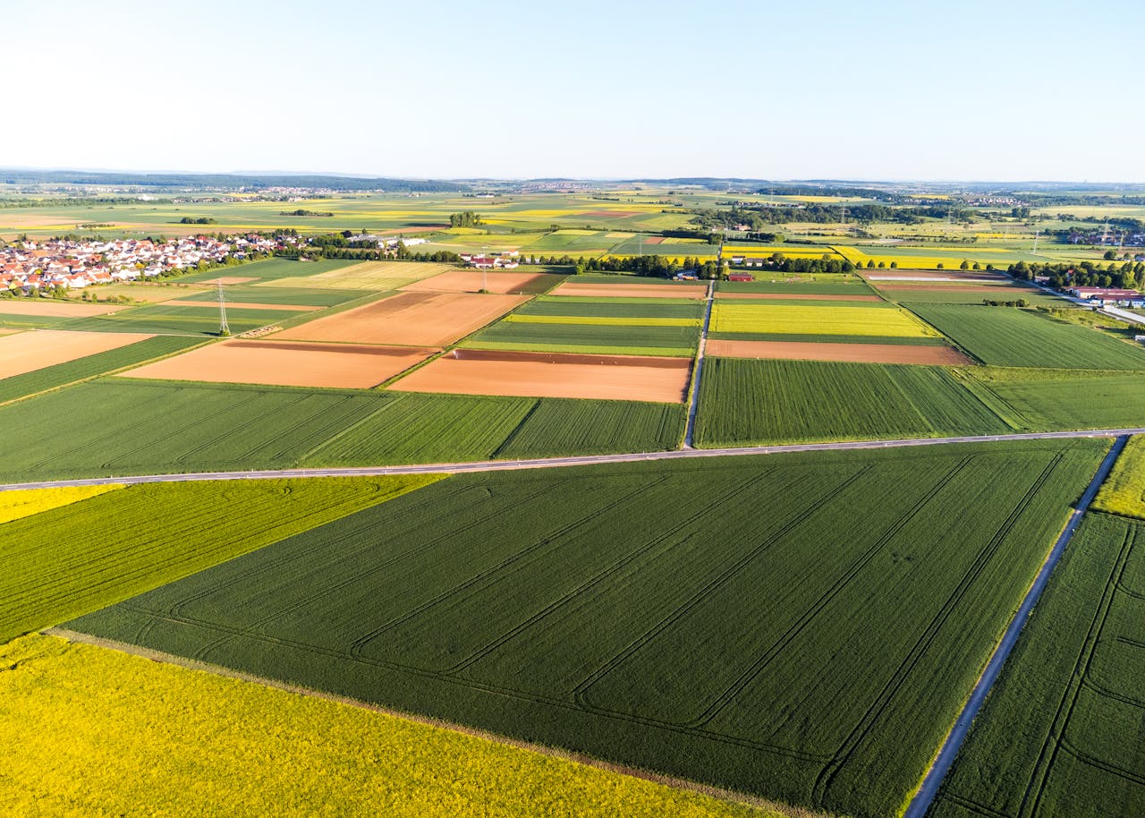 Stunning aerial view of vibrant patchwork agricultural fields and a distant village.